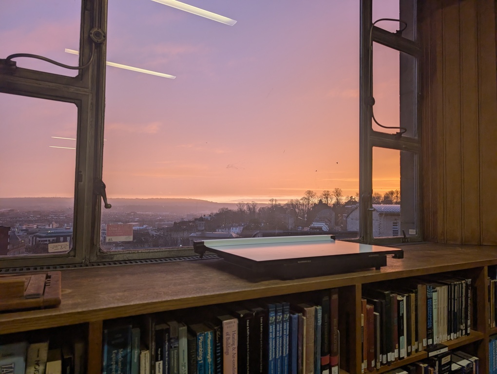 a window view inside of a library; there is a beautiful orange sunset view